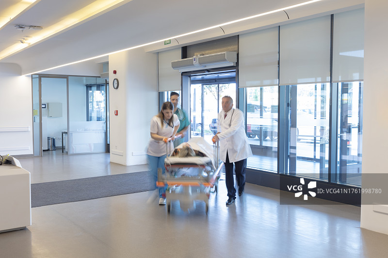 医护人员用担架将病人从救护车送到医院。两名医护人员和一名病人。现代救护车。大型医院急诊室入口图片素材
