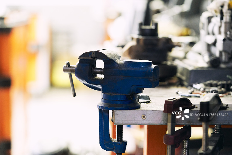 机械师工作台上带杠杆的蓝色虎钳及其他工具图片素材