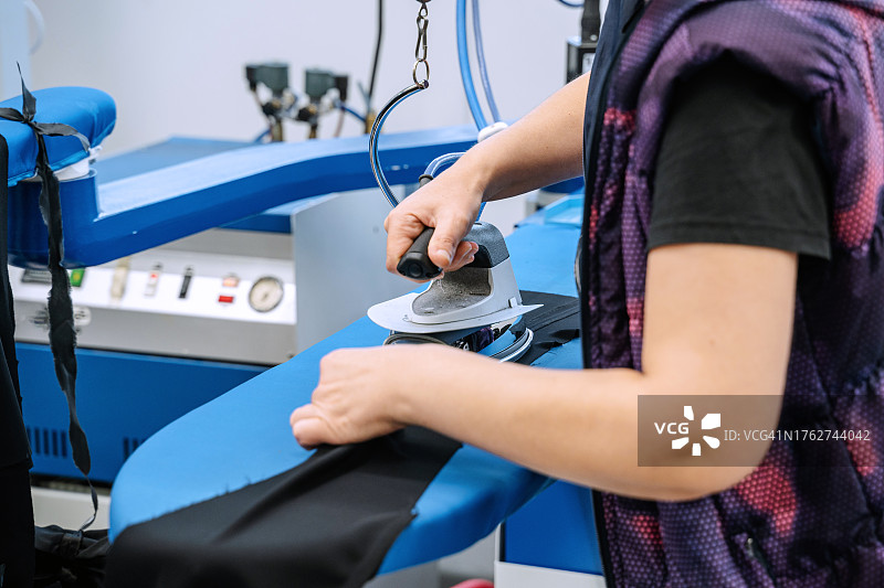 服装厂工人正在熨烫面料图片素材