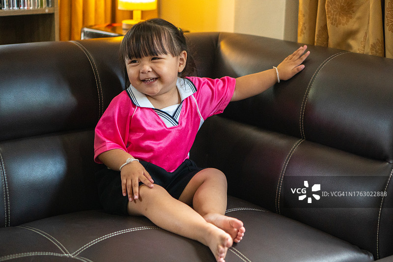 快乐的孩子在家里的沙发上跳舞。图片素材