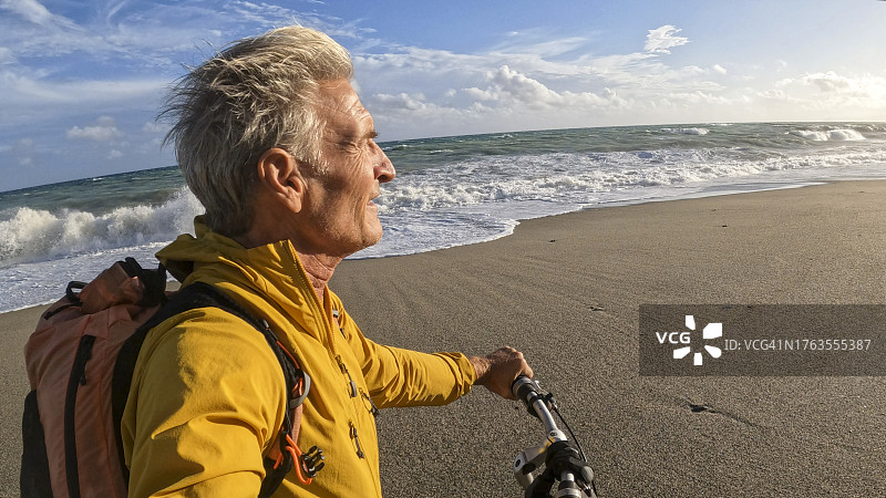 年长的男人在海滩上推着自行车图片素材
