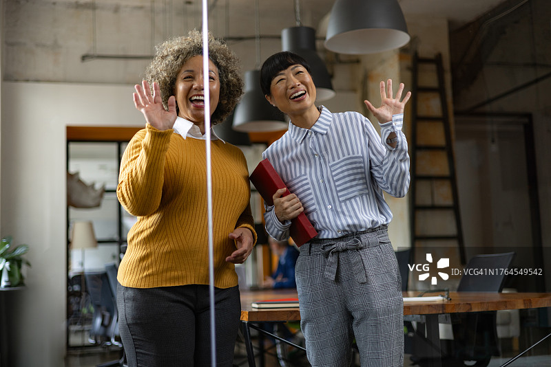 快乐的女商人在办公室通过互动屏幕进行视频通话图片素材