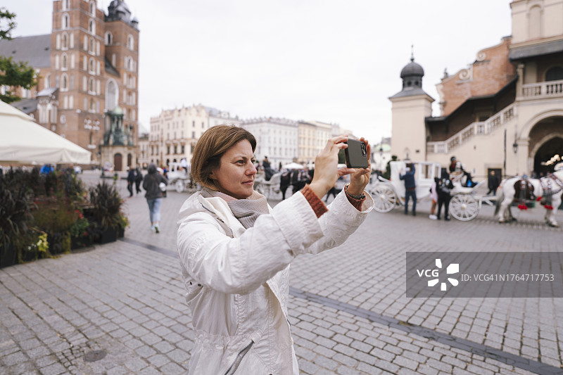 女人拍摄波兰克拉科夫中央集市广场和纺织会馆图片素材