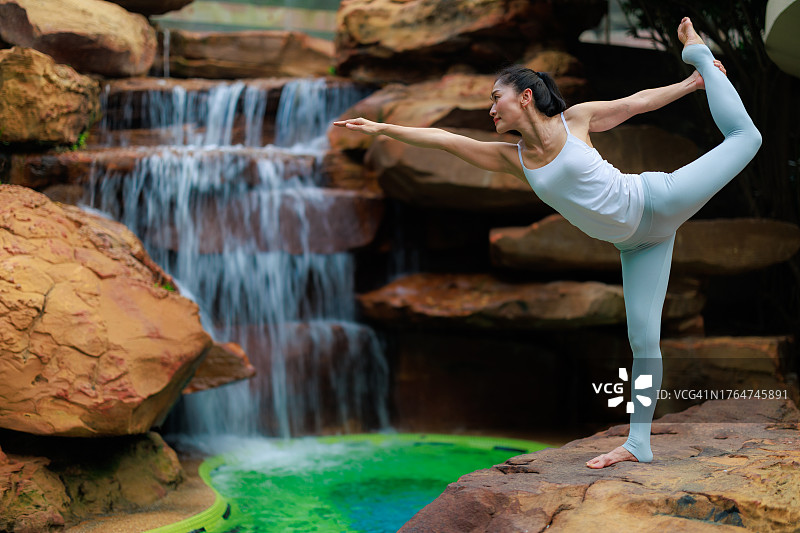 瑜伽冥想：亚洲女性在风景优美的瀑布旁冥想图片素材