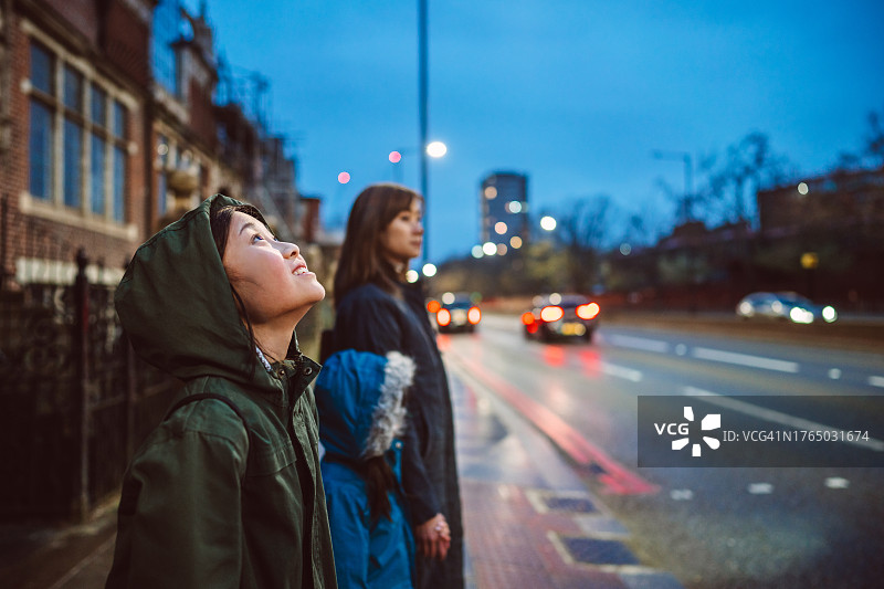 快乐的青少年女孩在城市街道上与家人一起等交通信号灯，仰望天空，充满希望图片素材