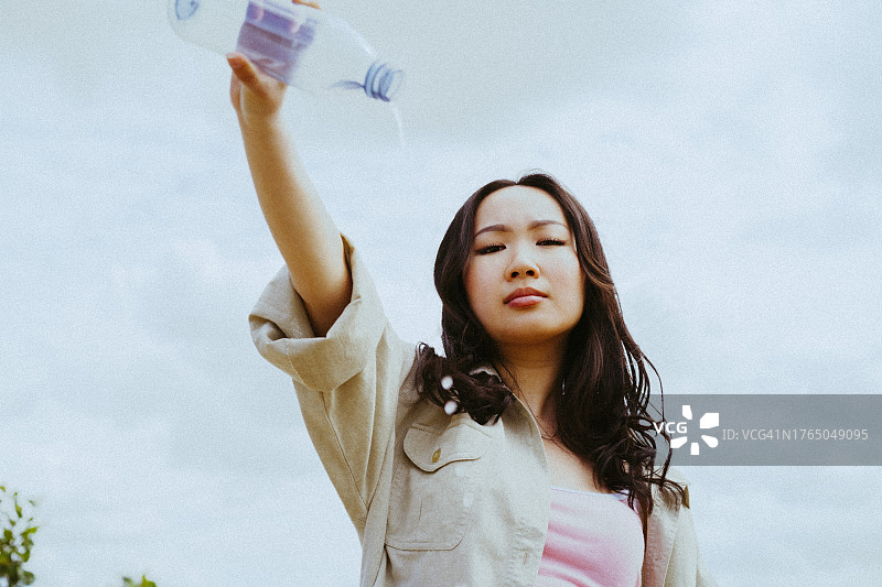 仰视角度拍摄的自信年轻女性倒水图片素材