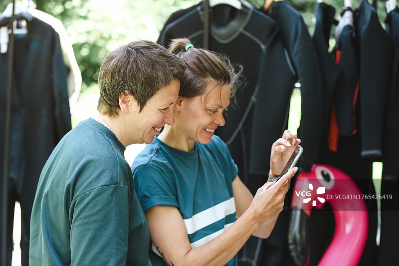 年长的冲浪女人们在滑水训练后一起放松，并在手机上查看数据图片素材