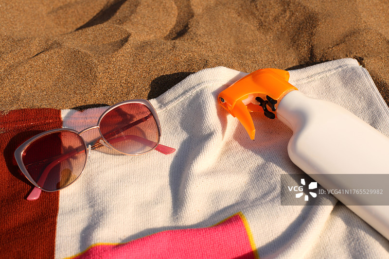 西班牙沙滩毛巾上的太阳镜和喷雾瓶高角度景观图片素材