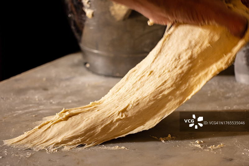 面包师在厨房桌子上擀面团的局部特写图片素材