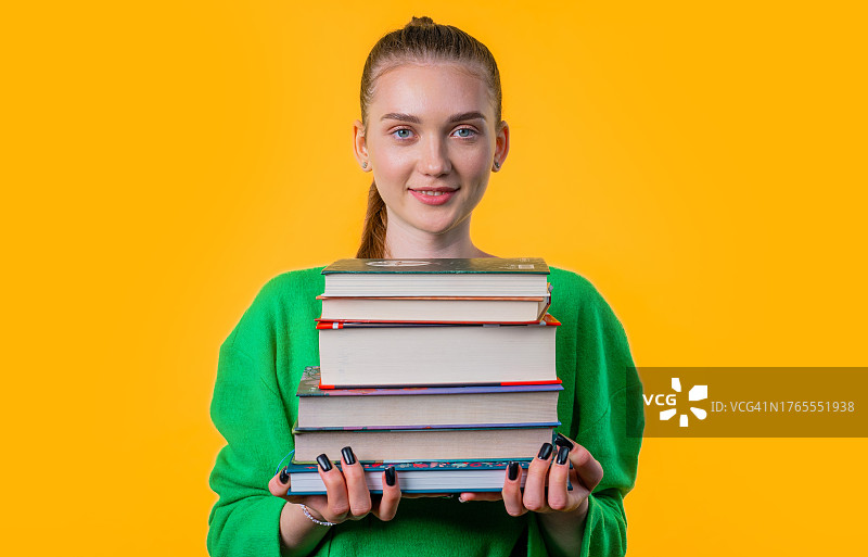 微笑的年轻女学生在图书馆拿着一堆书图片素材