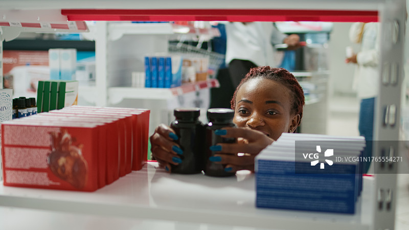女药剂师在药房货架上整理药品图片素材