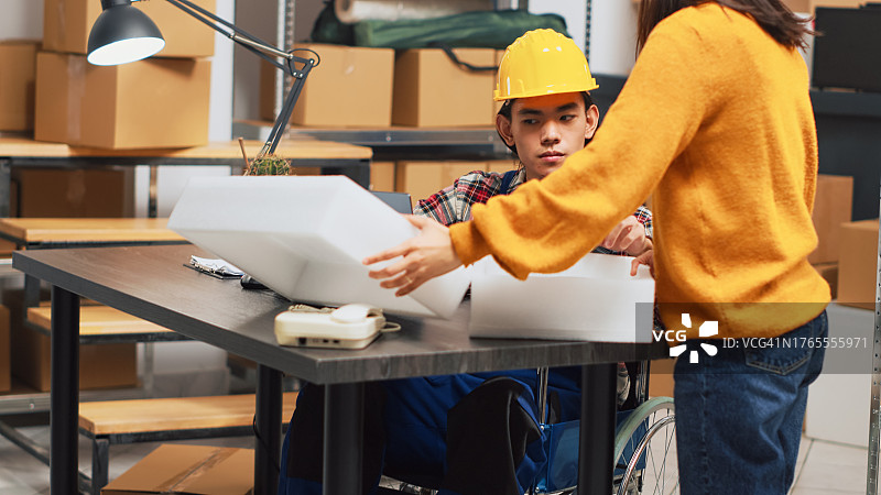 戴安全帽的年轻工人在仓库与女同事工作图片素材