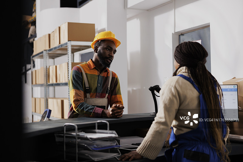 仓库工人在柜台与同事讨论货物运输图片素材