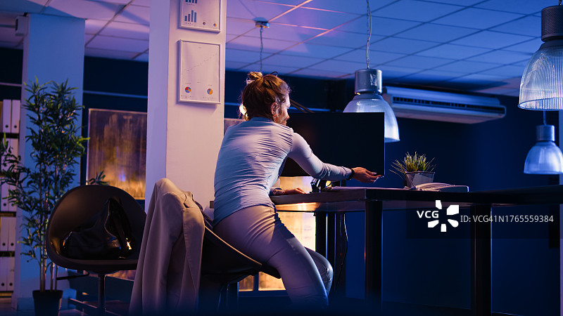 深夜，女员工关闭电脑准备起身离开办公室的侧视图图片素材