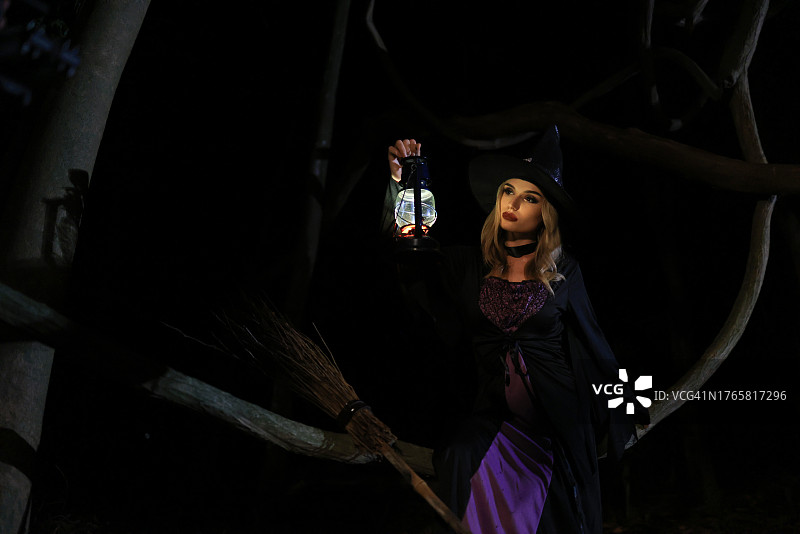 万圣节之夜，迷人的女巫在森林里拿着灯笼图片素材