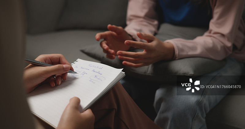 亚洲治疗师在与女患者的治疗过程中记录笔记图片素材