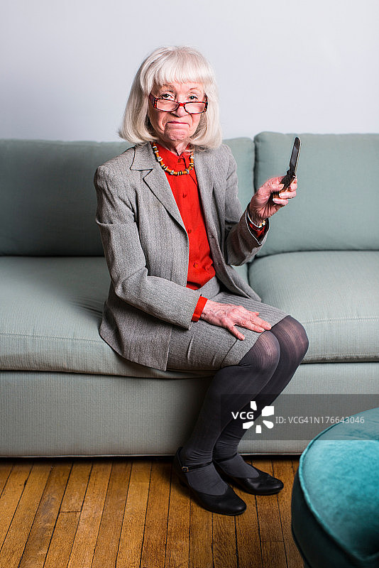 年长的女人坐在沙发上拿着手机图片素材
