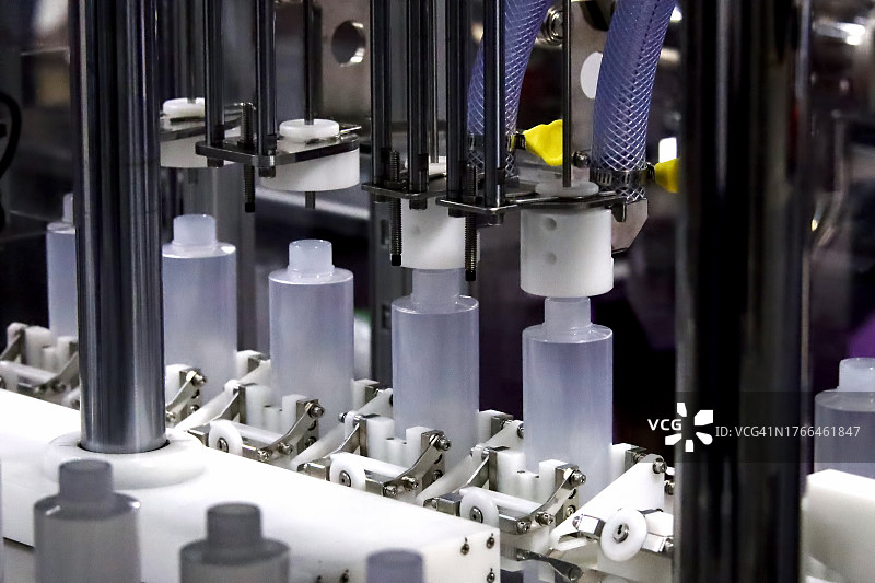 化妆品生产线上自动压盖贴标机的白色塑料瓶图片素材