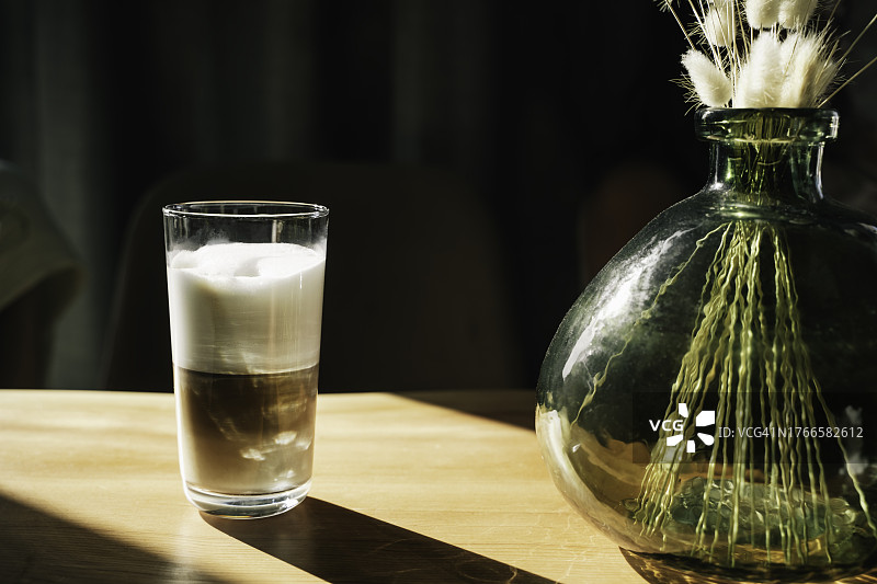 阳光下木桌上的一杯拿铁图片素材