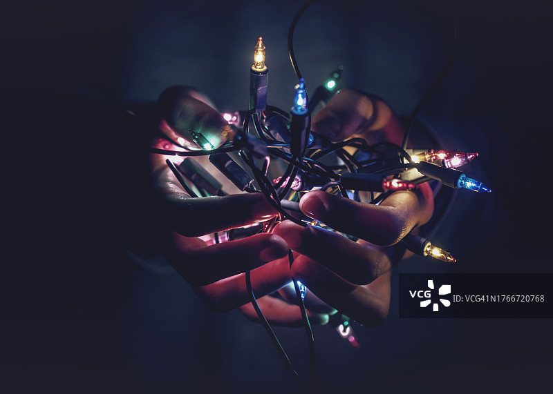 手捧发光彩色圣诞灯串特写图片素材