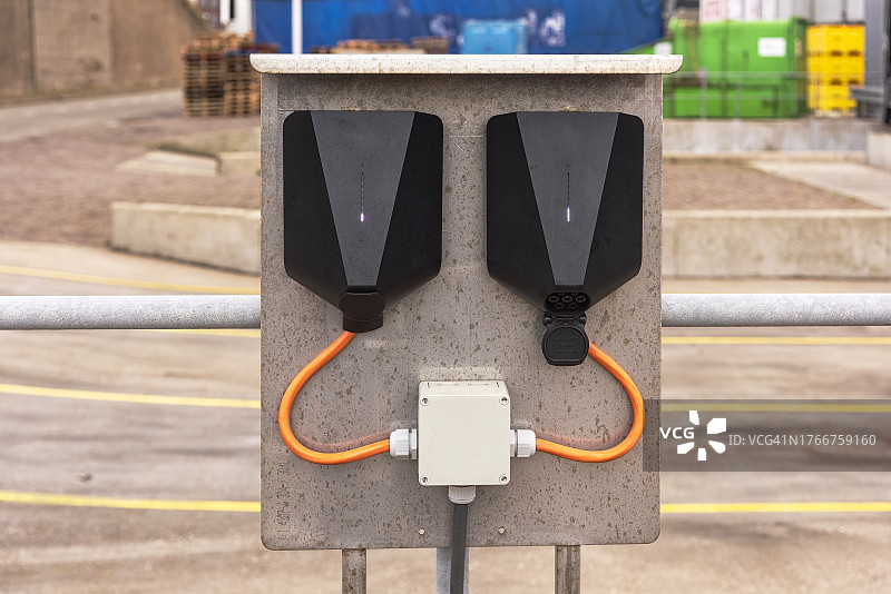 两个带橙色电缆的黑色Easee充电装置图片素材