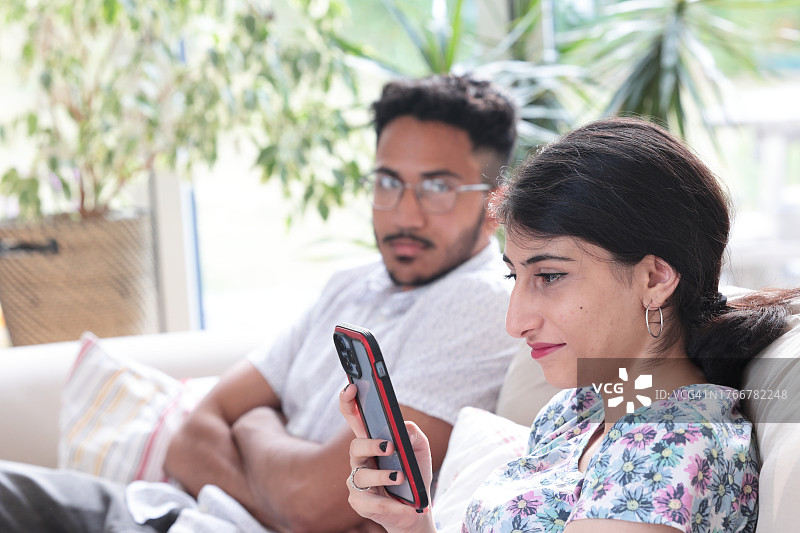 男人看着正在看手机的女人图片素材