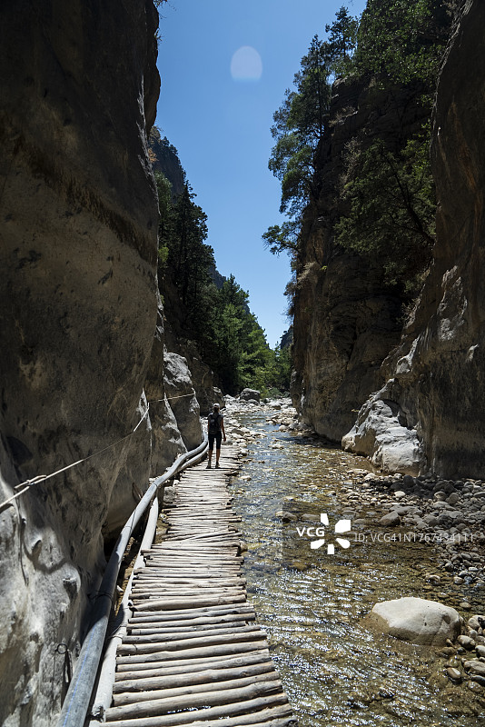 女子独自在萨马利亚峡谷徒步，欣赏岩石山丘和河流的景色图片素材
