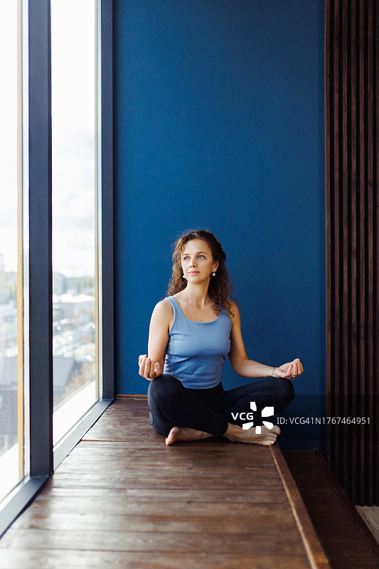 美丽女瑜伽士木窗边莲花坐姿图片素材