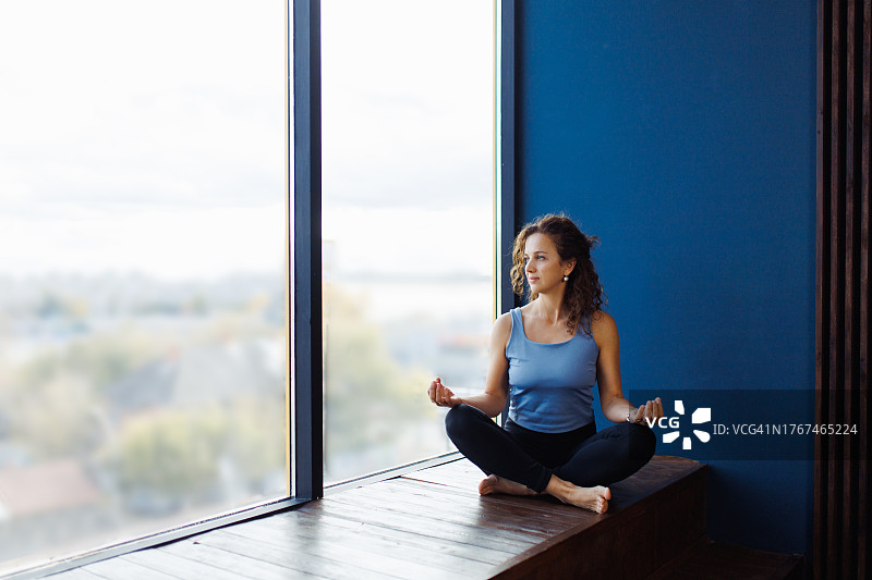 练习瑜伽的女子在窗台上优雅地进行莲花坐图片素材