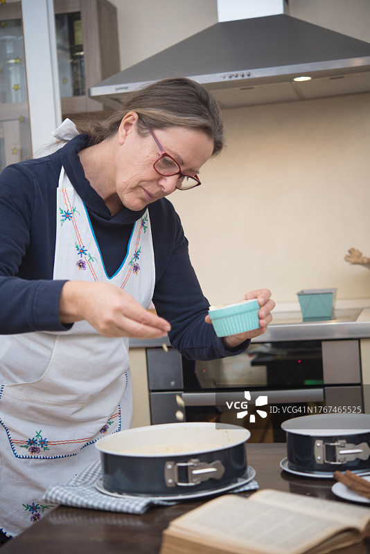 年长女性在甜面团上撒杏仁片图片素材