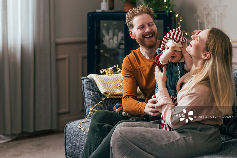 圣诞欢乐：父母和宝宝在沙发上玩耍图片素材