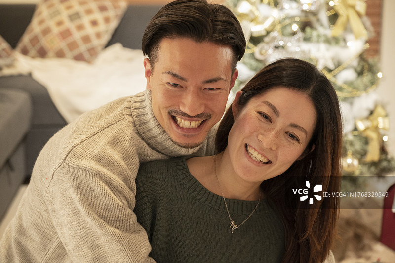 情侣在客厅的圣诞树前拥抱图片素材