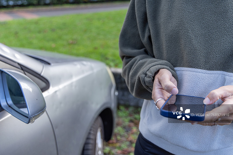 冰雹损坏汽车后，联系汽车保险的女人图片素材
