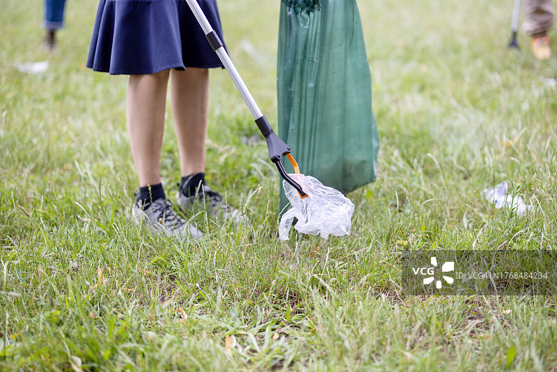 在公园用夹子和垃圾袋捡垃圾的女志愿者特写图片素材