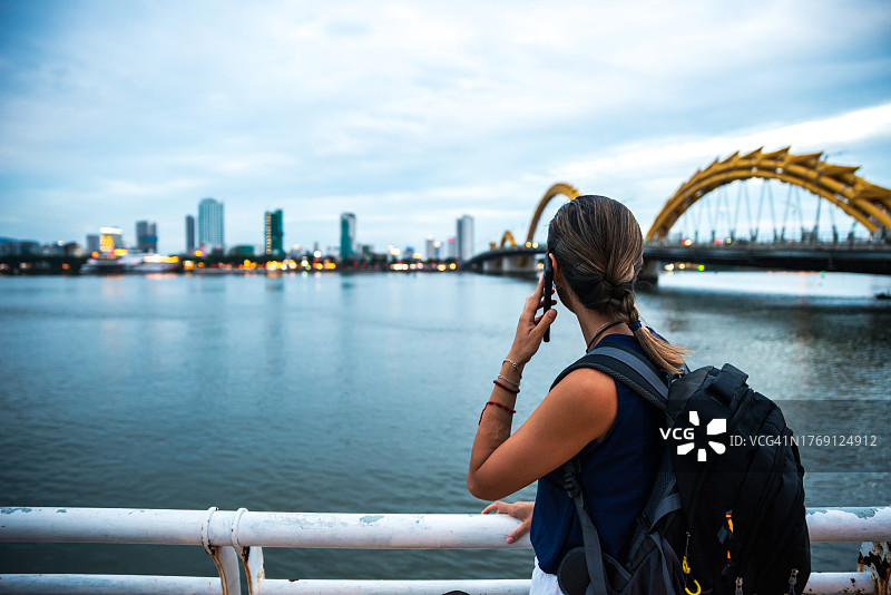 在岘港市的背景下，数字游民正在用手机交谈图片素材