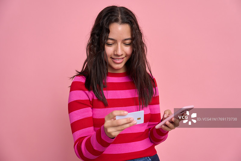 年轻女人用智能手机在网上支付购物，持有银行卡。图片素材