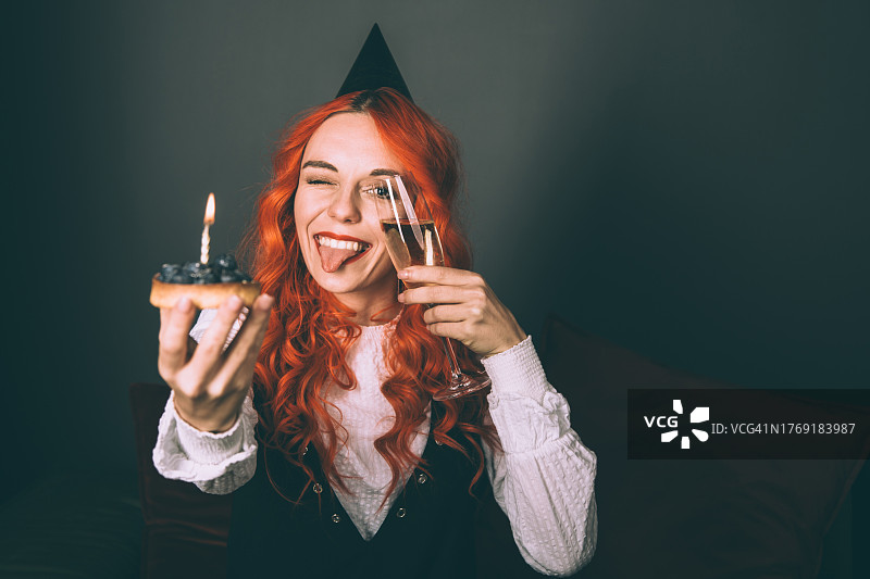 手拿生日蛋糕和一杯香槟的年轻女子图片素材