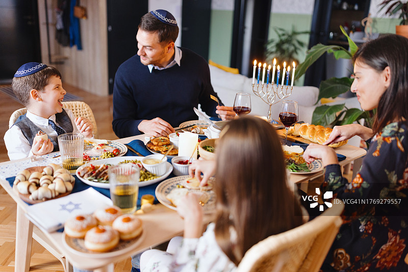 光明节吃传统犹太食物的微笑家庭图片素材