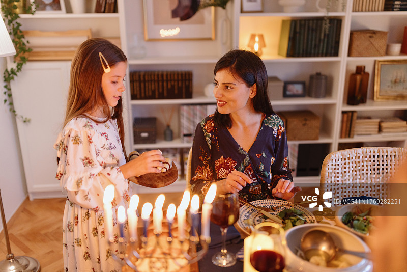 女儿在传统光明节晚餐上给母亲鲁格拉赫点心图片素材