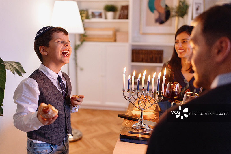 快乐儿童在光明节吃Sufganiyot图片素材