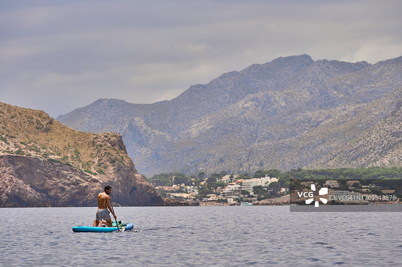男子跪在湖中的桨板上图片素材
