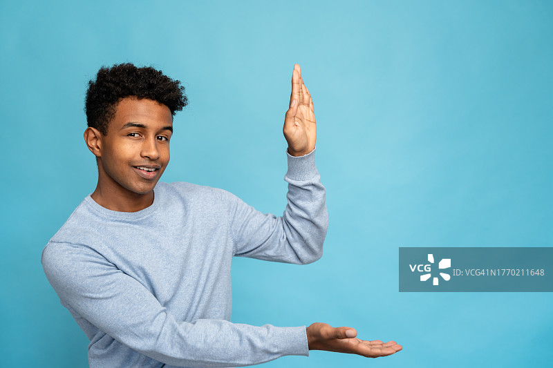 非裔美国男人在蓝色背景下做手势图片素材