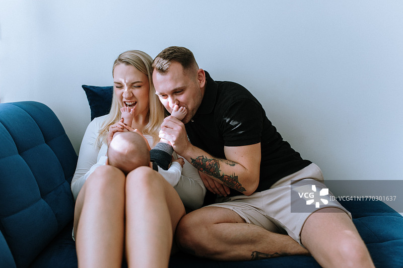 幸福的夫妇和男婴亲密互动，逗弄孩子的小脚并亲吻图片素材