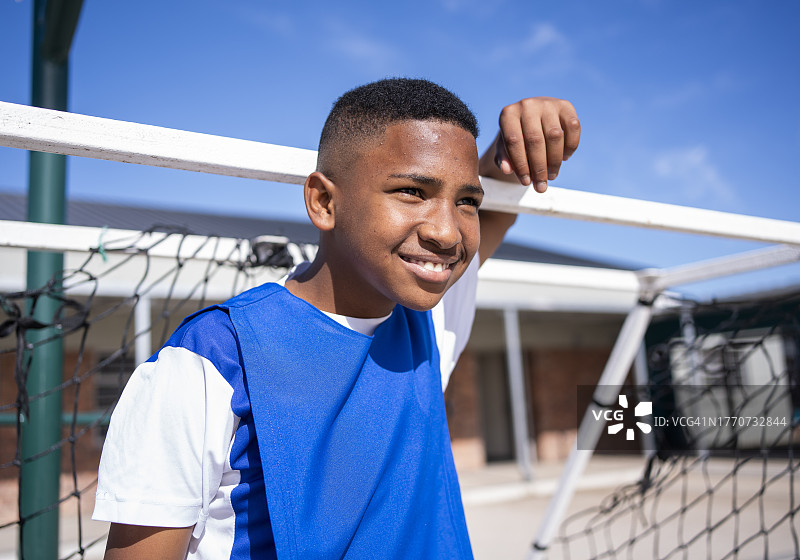 小学生站在学校足球场的球门柱旁图片素材