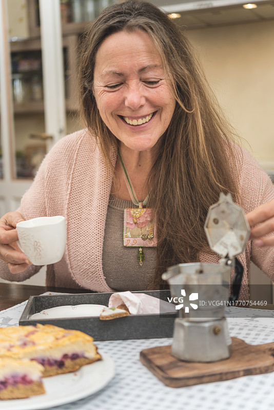 快乐的老年妇女在摩卡壶中寻找更多咖啡图片素材
