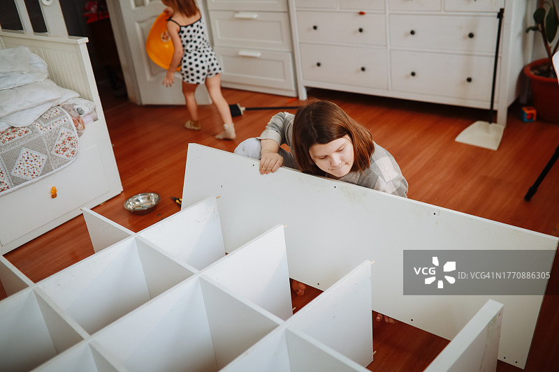 超重青少年居家坐着组装家具图片素材