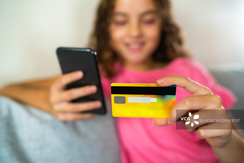 年轻少女用智能手机拿着信用卡图片素材