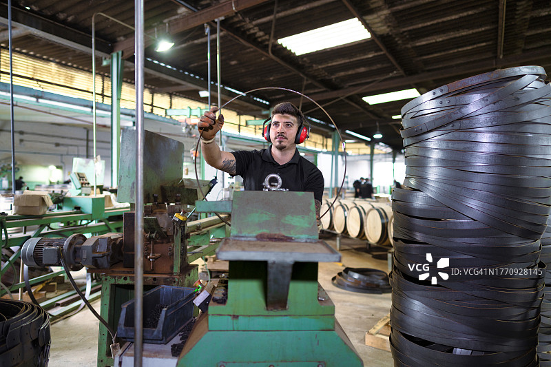 雪利酒桶车间里，制桶大师正在制作支撑桶骨架的金属条图片素材
