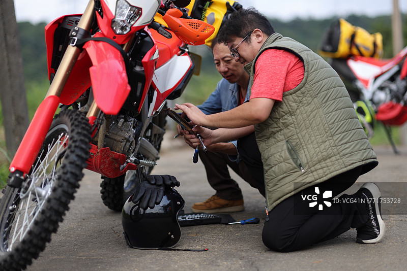 两个男人骑摩托车露营，正在检修摩托车图片素材