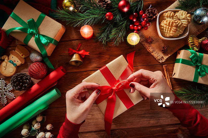 在乡村木桌上，女人在圣诞礼物上系着蕾丝图片素材